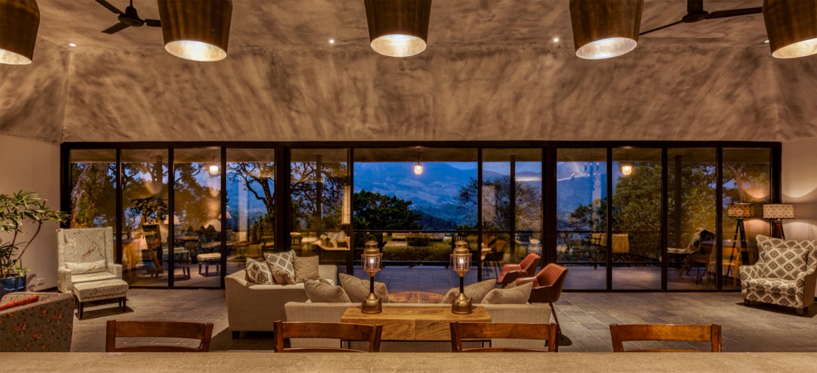 A modern living room featuring two large windows, minimalist design, and warm wooden floors and furniture, highlighting a seamless blend of comfort and architectural elegance.